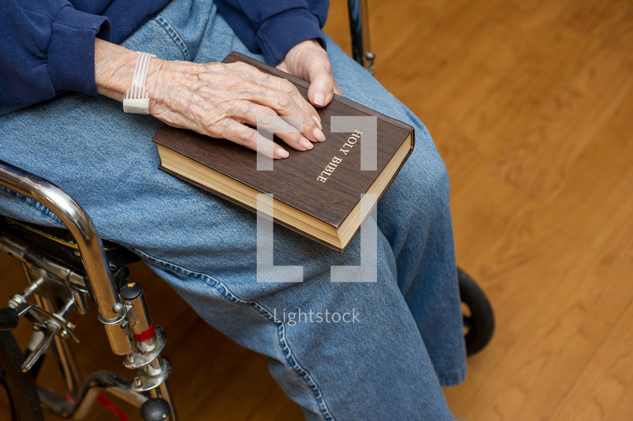 elderly woman in a wheelchair holding a Bible
