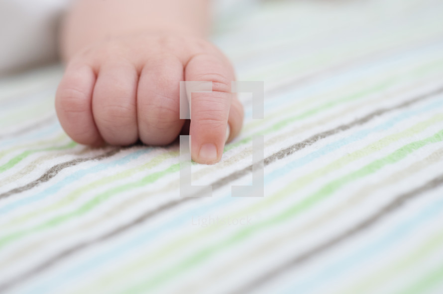 infant's hand on a blanket 