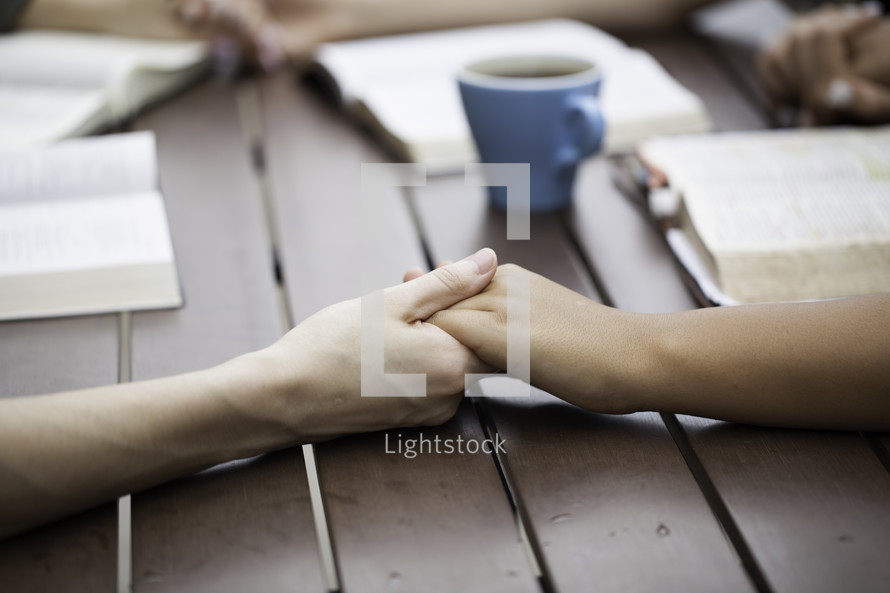 girls holding hands in prayer around a table 
