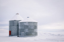 steel grain bins in winter landscape