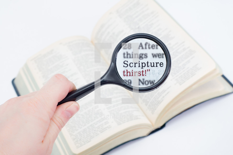 Hand holding a magnifying glass over Bible text "scripture thirst."