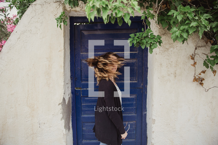 woman shaking her head standing in front of a blue door 