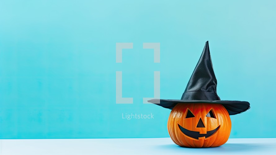 Halloween pumpkin with witch hat on blue background. Copy space.