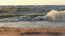 Ocean waves crashing onto shore at sunset.