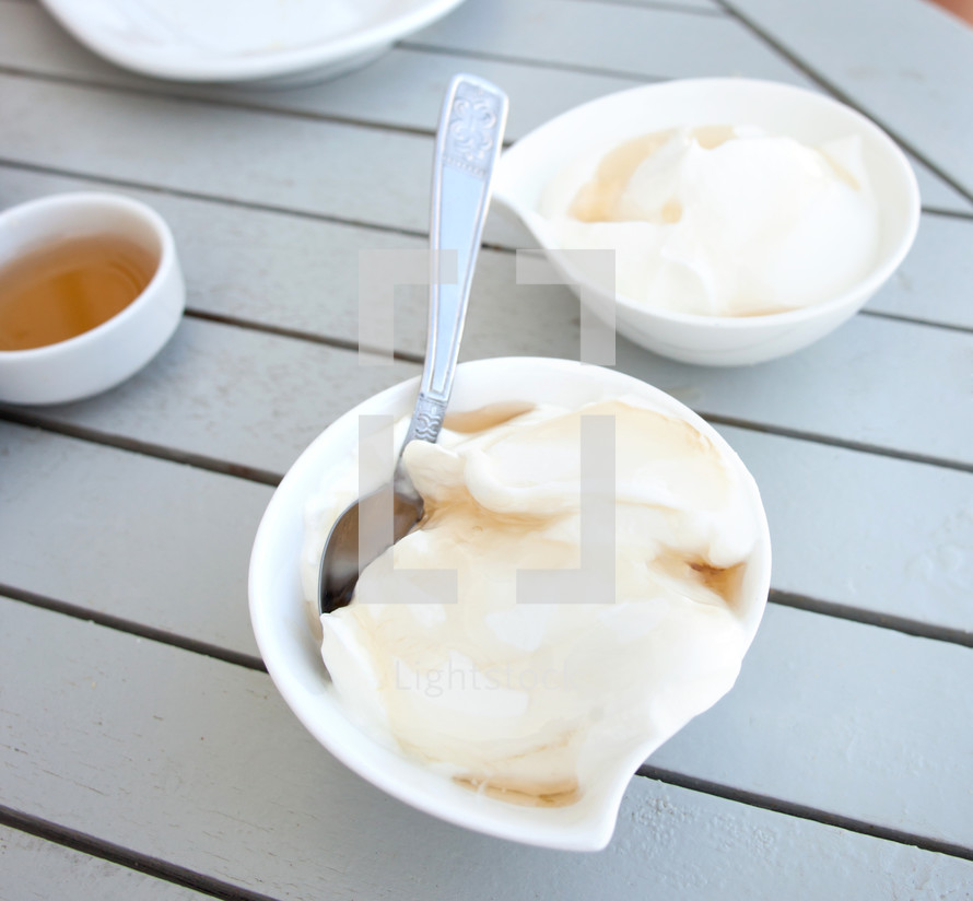 Greek yogurt with honey in a pot on wooden table