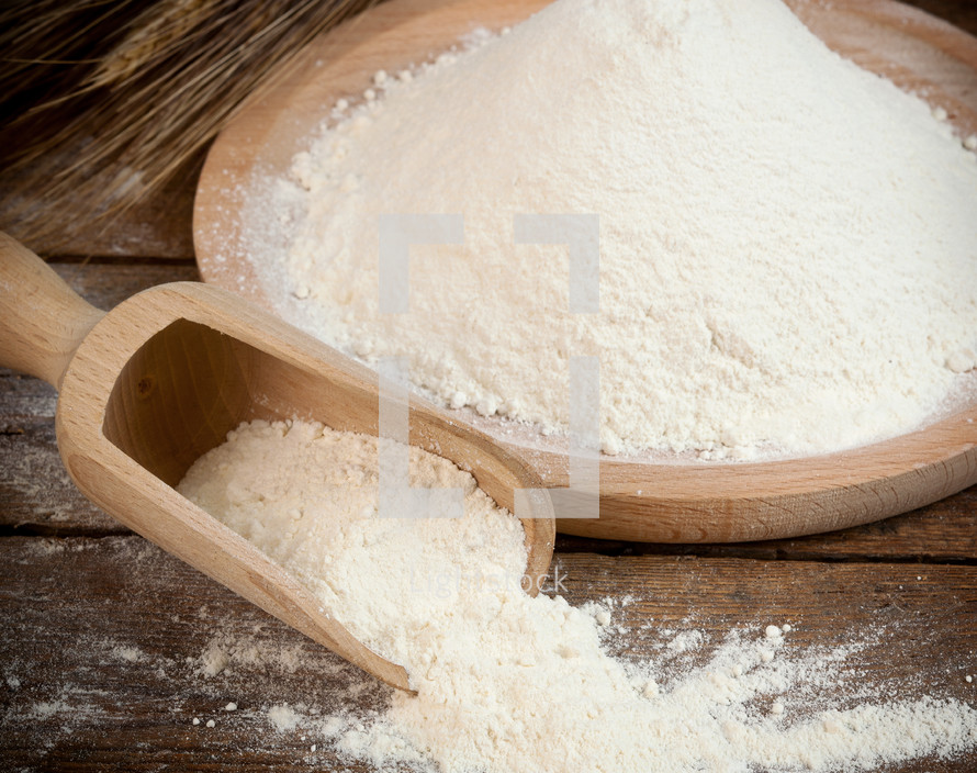 Wooden spoon with white flour for bread and cakes.