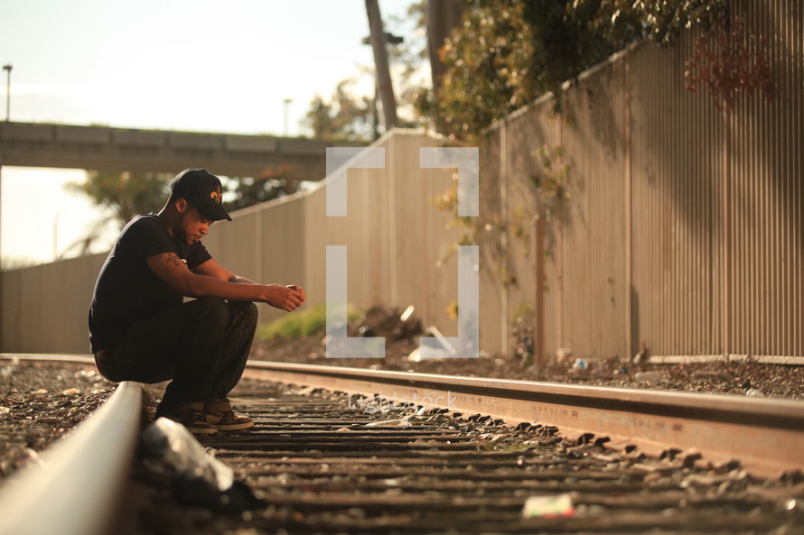 Man sitting on railroad tracks