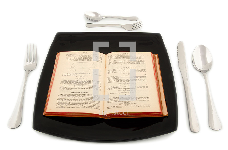 physics book in the plate with cutlery on white table.