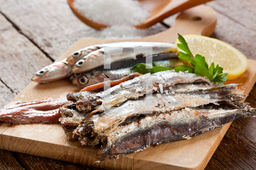 Marinated anchovies with salt and lemon on wooden table