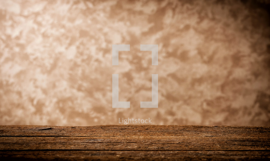 Selective focus on wooden table on blurred beige grunge wall