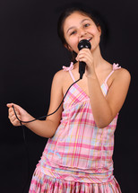Little girl sings with microphone on black background