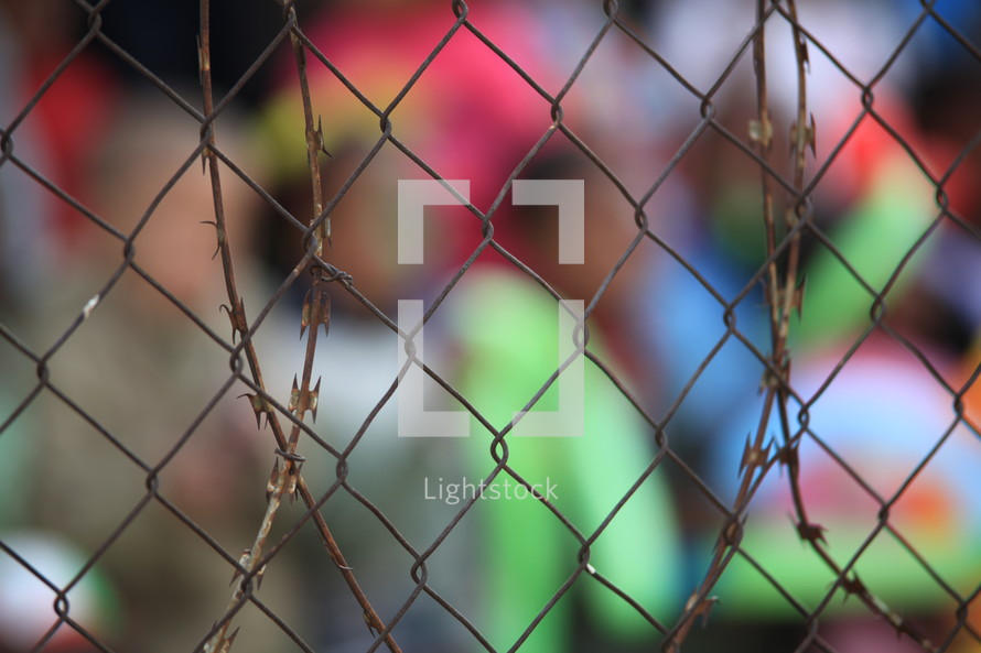 People out of focus, behind a fence