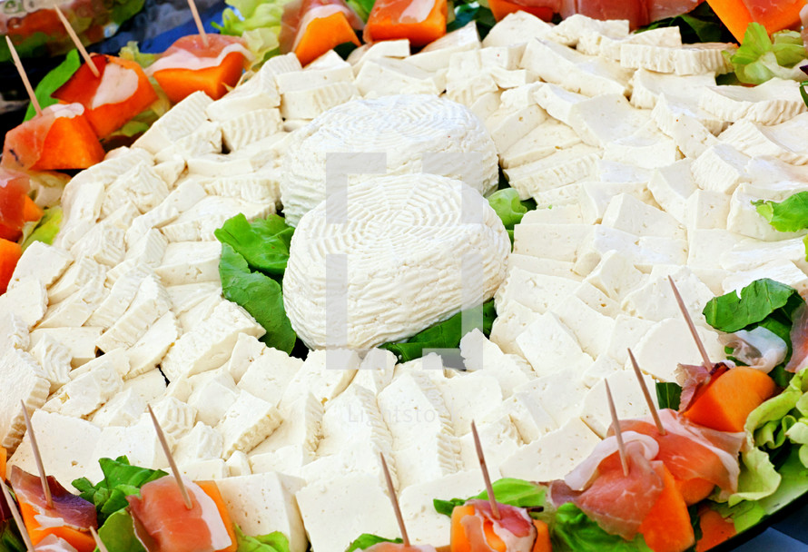 Ricotta cheese, typical Italian cheese product, surrounded by ham and melon.