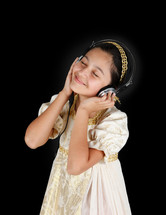 Young girl in ancient dress while listening music with headphones on black background.
