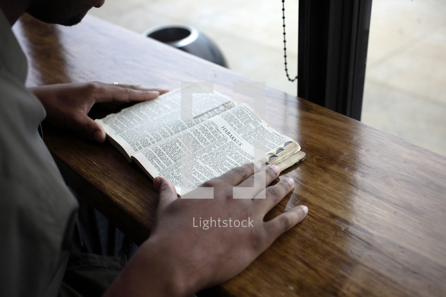 Man reading an open Bible on a table.