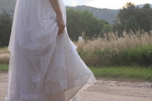 a bride holding the bottom of her wedding gown 