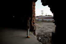 a person standing in front of a hole in an abandoned building 