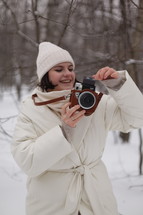 a woman holding a camera standing in snow 