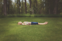 young girl laying in the grass alone