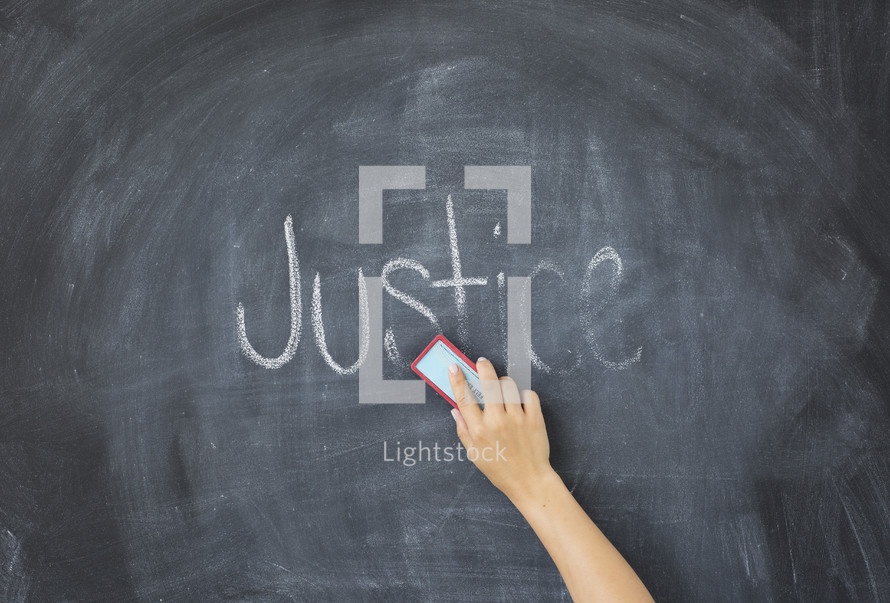 erasing the word Justice off a chalkboard 
