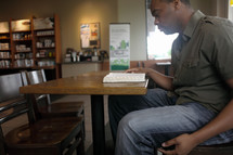 Man reading the Bible in a coffee shop.