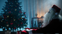 Santa Claus looks at unlit Christmas tree