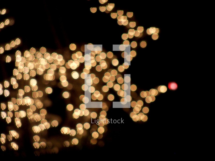 A dazzling array of white Christmas lights appear in the background lighting up the night sky  in the shape of a reindeer with decorative Christmas light bulbs that bring a warmth to the night air.