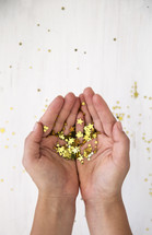cupped hands holding star confetti 