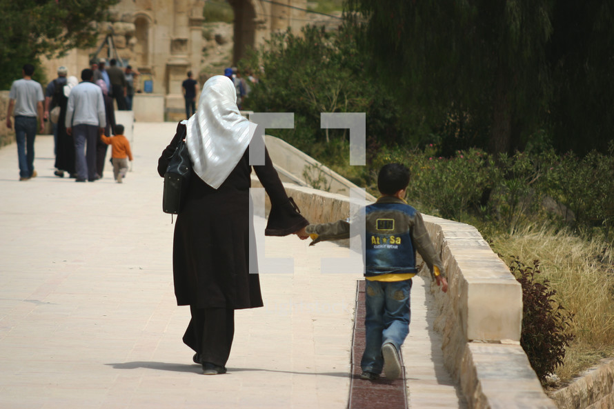 a mother walking holding hands with her son 