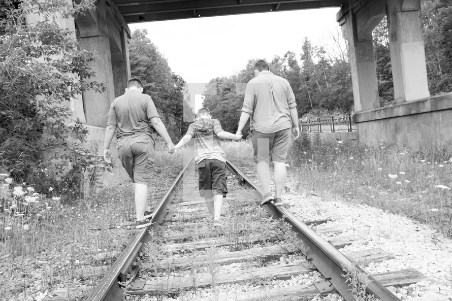 boys walking on train tracks 