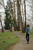 a woman standing on a path looking out in the distance 