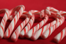 Peppermint candy canes lined up on a red tablecloth.