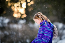 a girl child in a winter coat standing outdoors in snow 