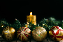gold ornaments, pine garland, Christmas lights, and candle 