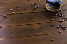Coffee beans and a coffee cup on a wooden surface.