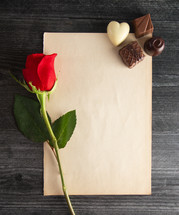 chocolates, long stem rose, and blank paper 