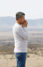 a man in prayer with a desert mountain view 