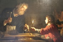 Painting depicting Joseph, carpenter and wood worker, chiseling by candlelight with his son Jesus looking on.