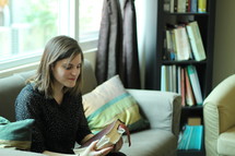 a woman holding a Bible while sitting on a couch 