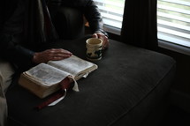 a man reading a Bible by a window 