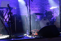 drum set, microphones, and guitar on stage under spot lights 