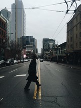 man in a trench coat crossing a street 