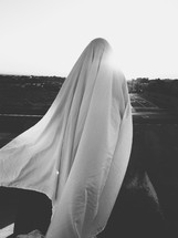 a woman under a white sheet outdoors 