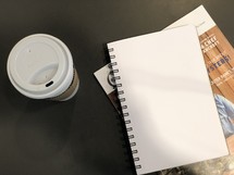 to go coffee cup and notebooks on a table 