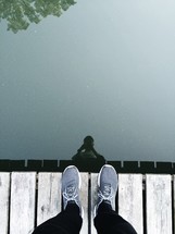 reflection of a man standing on a dock in lake water 