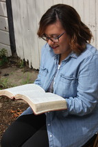  a woman in a chair reading a Bible outdoors 