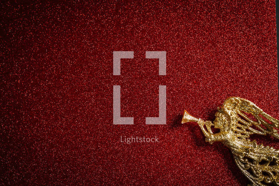 gold angel ornament on a red glittery background 
