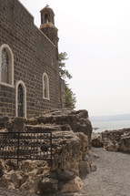 stone church with bell tower along a shore 