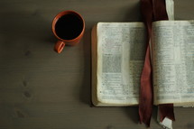 an open Bible and coffee mug on a coffee table