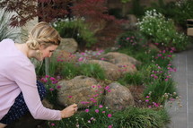 a woman with braided hair picking flowers in a backyard